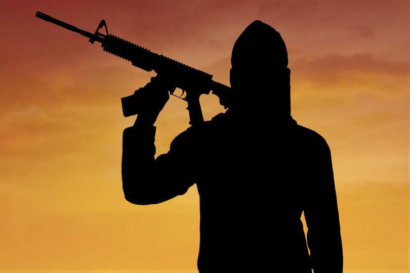 Terrorism concept: Silhouette of male radical muslim holding a machine gun