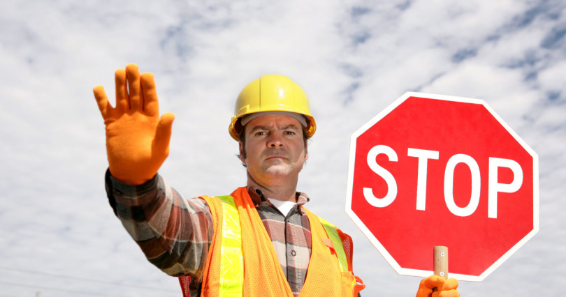 A construction worker stopping traffic, holding a stop sign.